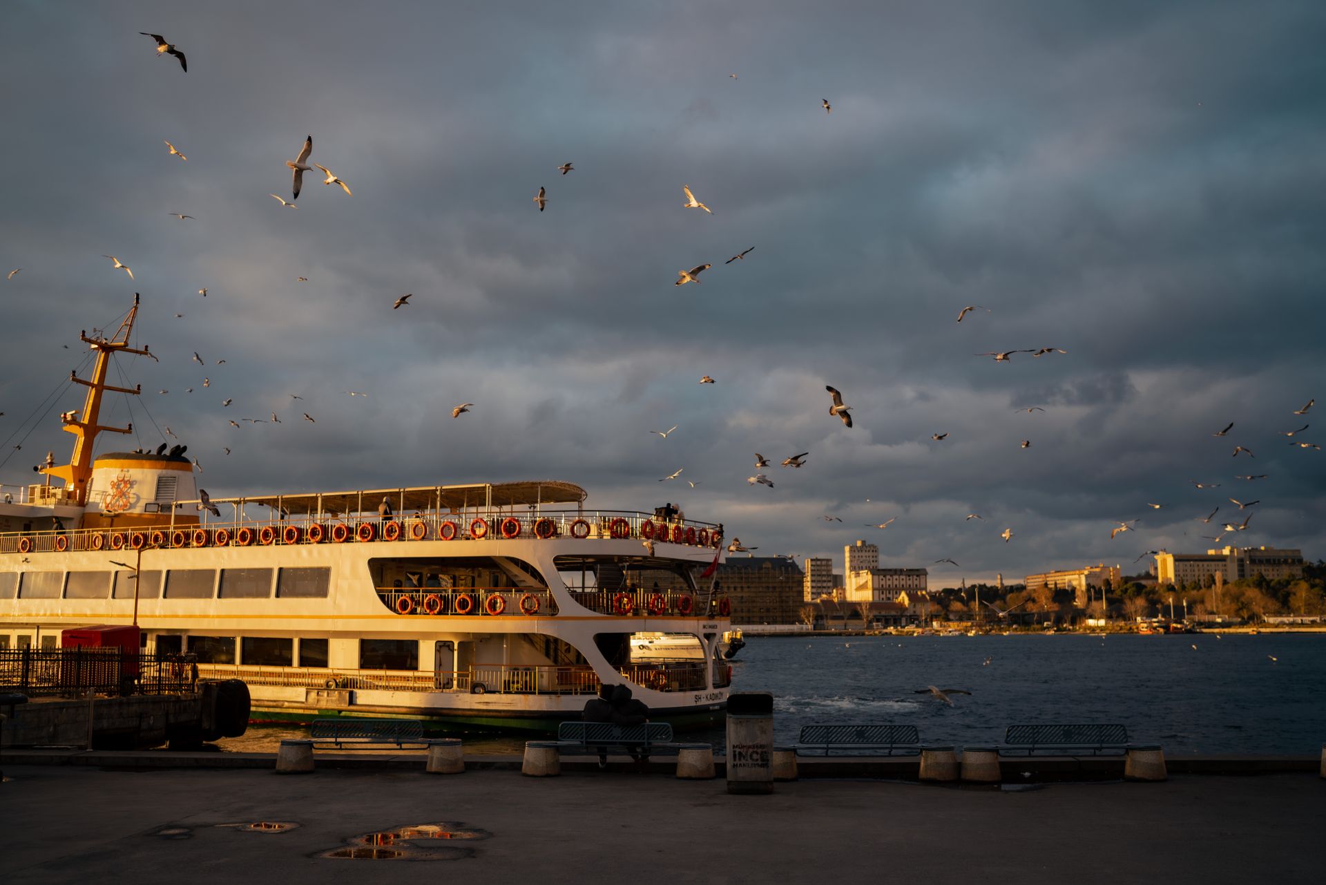 Golden sunset reflecting over calm Bosphorus strait waters with the wake of a distant ferryboat.