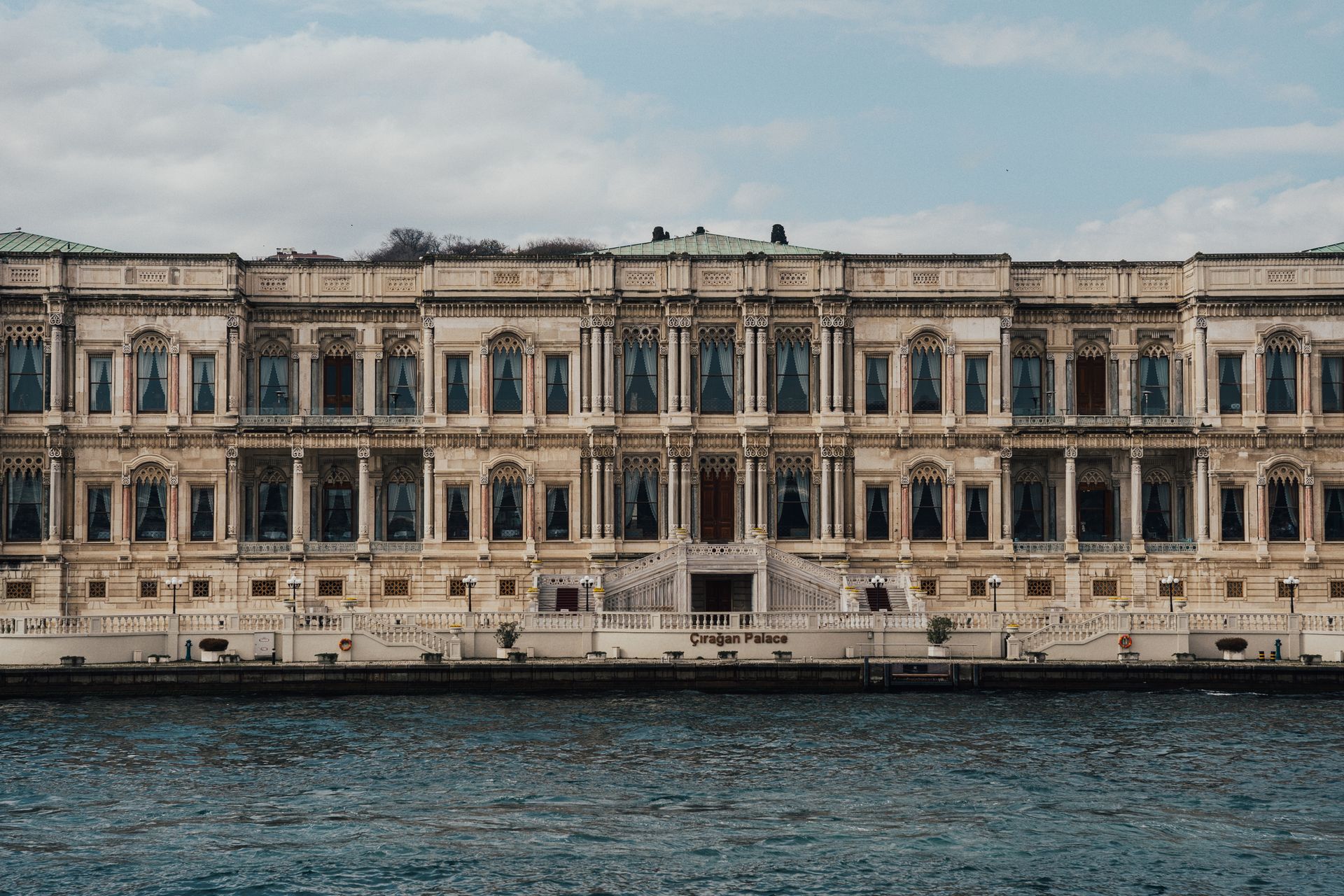 Historic stone facade and marble waterfront colonnade of Çırağan Palace Kempinski on the Bosphorus strait.