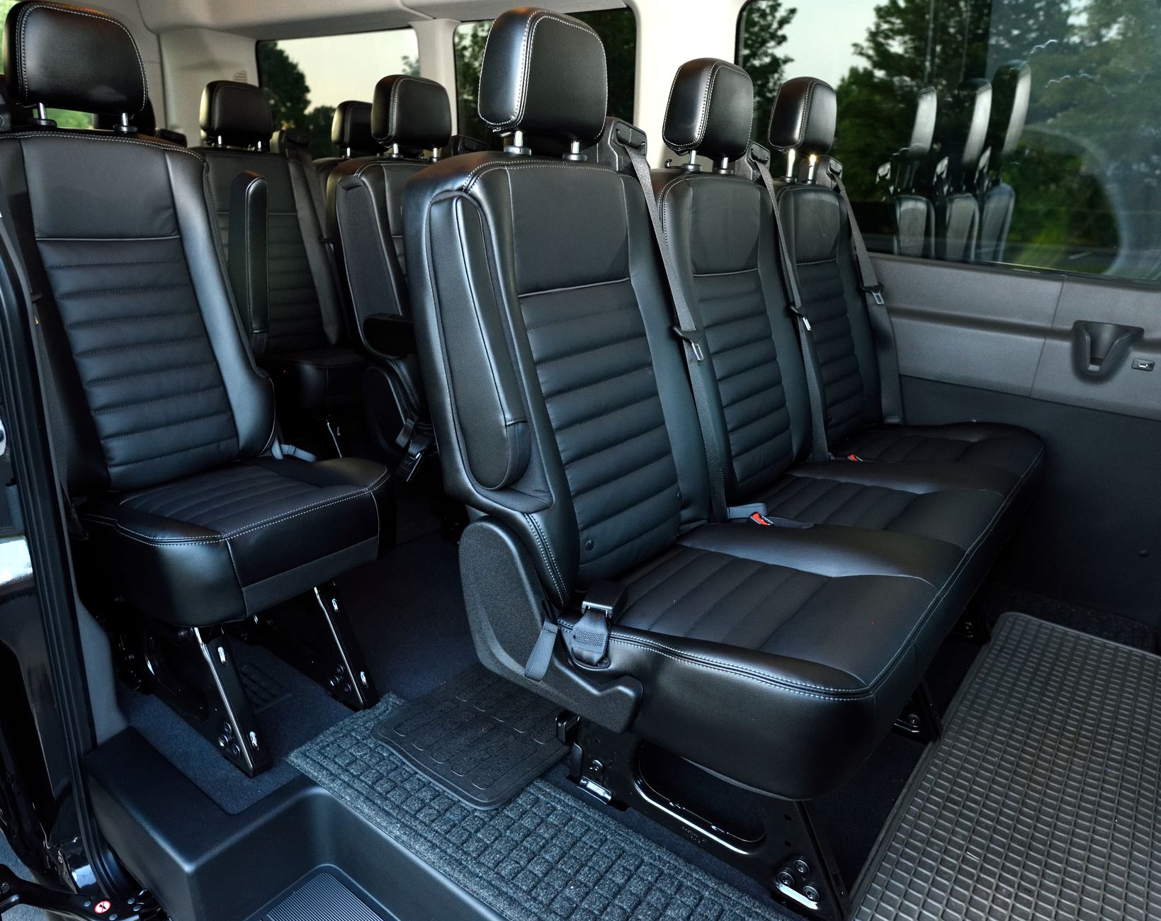 Spacious luxury interior of an executive passenger van with ergonomic leather seating and ambient lighting.