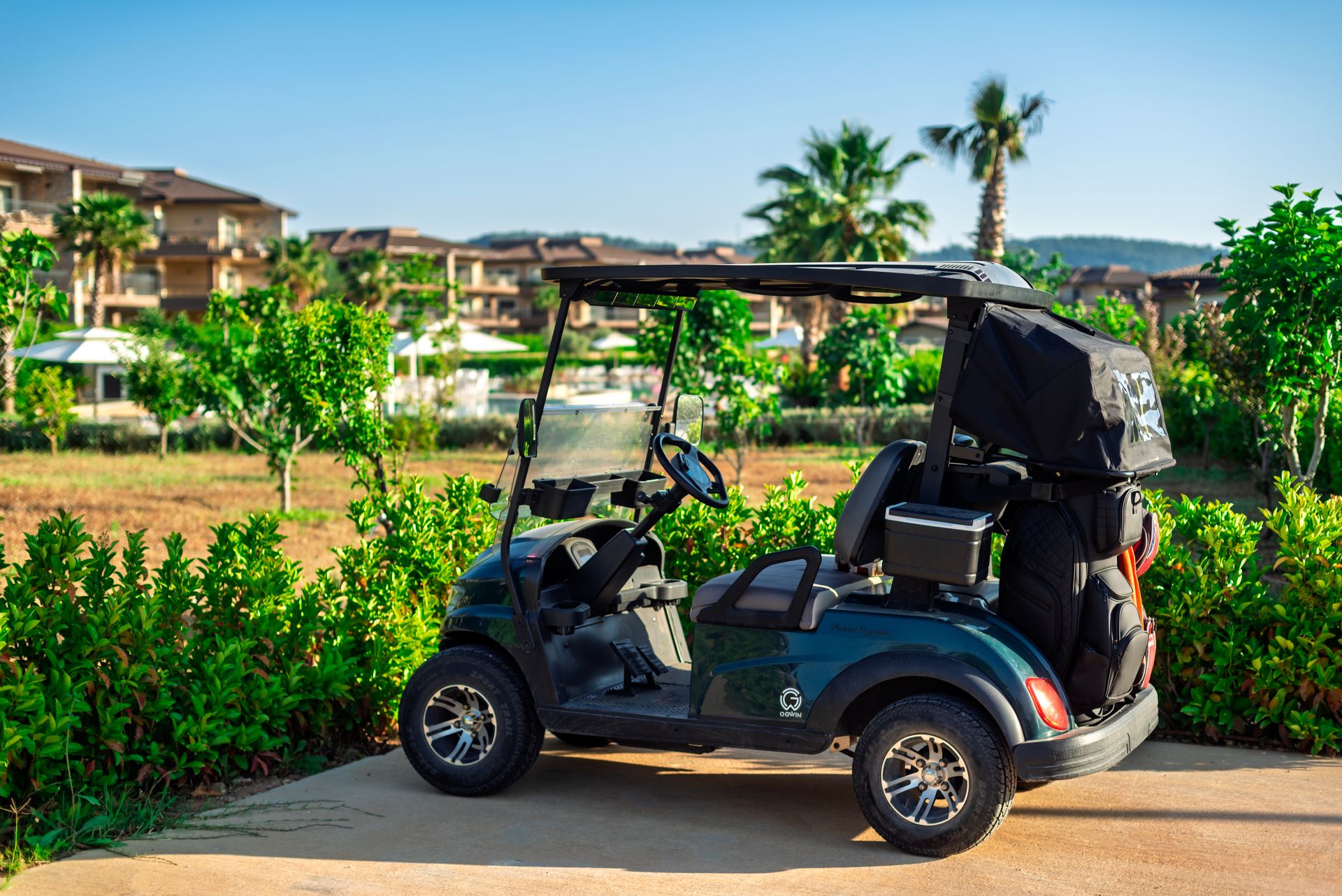 White electric utility buggy and luggage transport cart parked ready to shuttle guest baggage through pedestrianized streets.