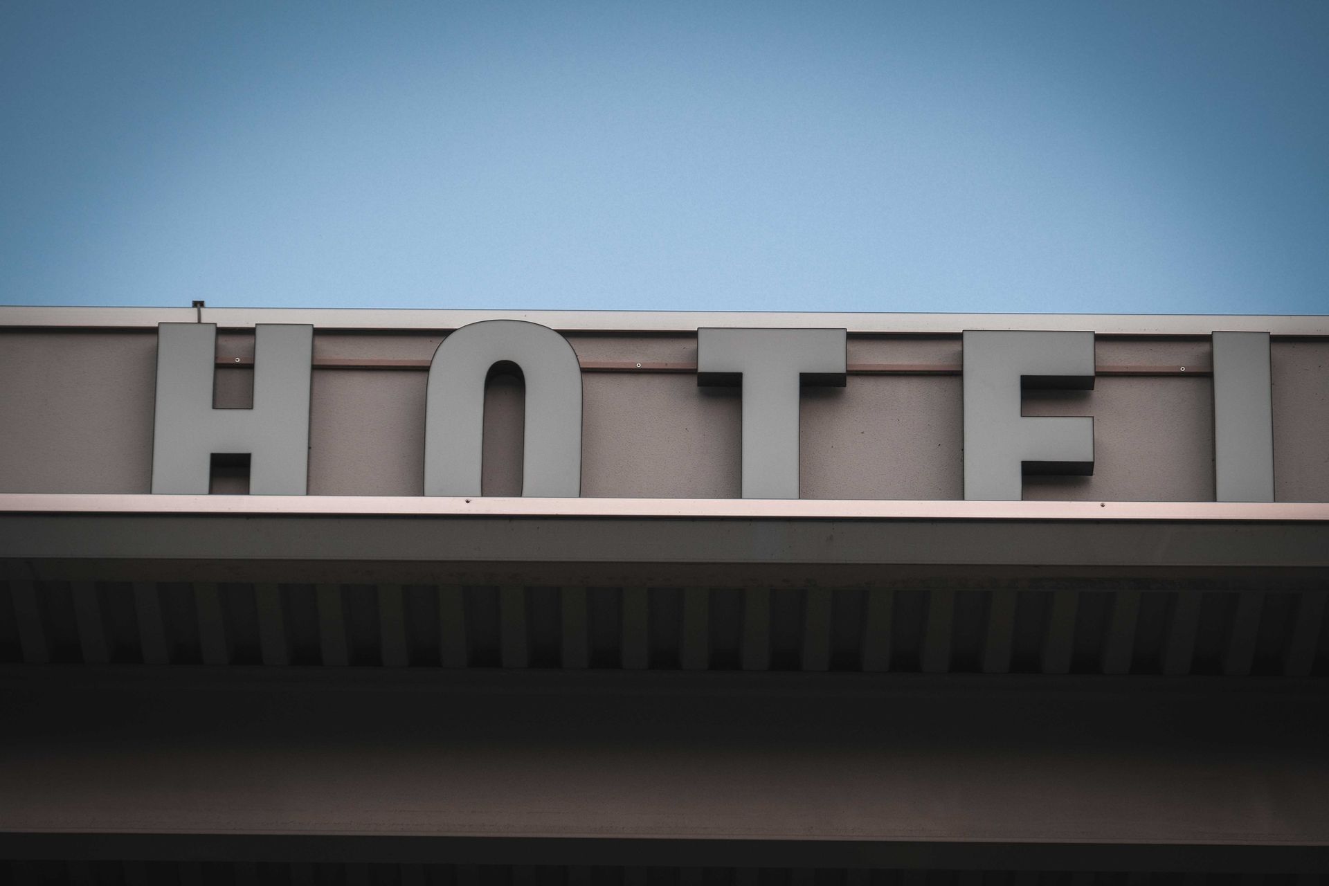 Modern glass and steel business hotel building exterior with signage under a clear blue sky.