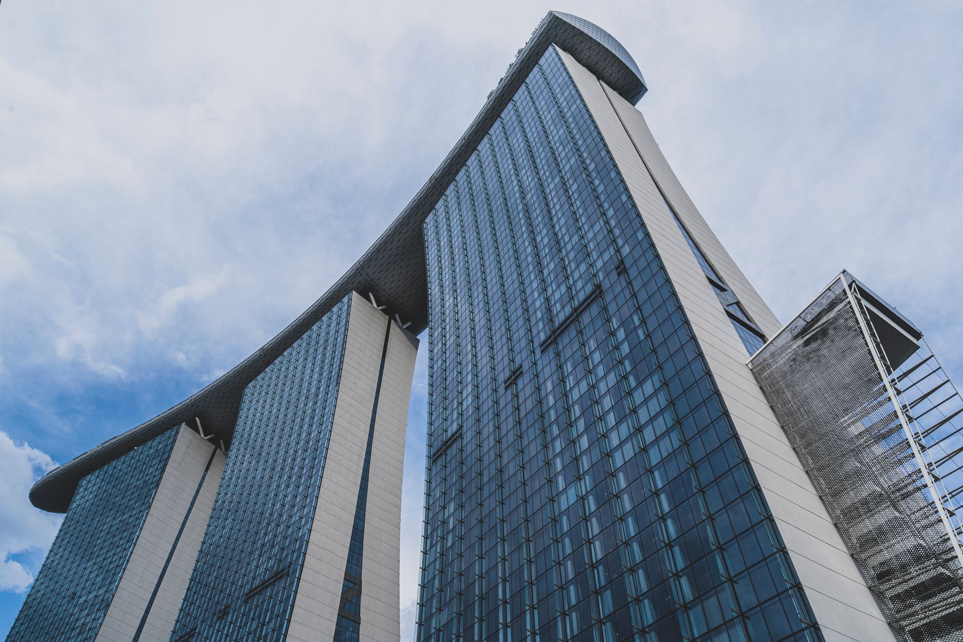 Contemporary high-rise glass hotel tower soaring into the blue sky with reflective facade panels.