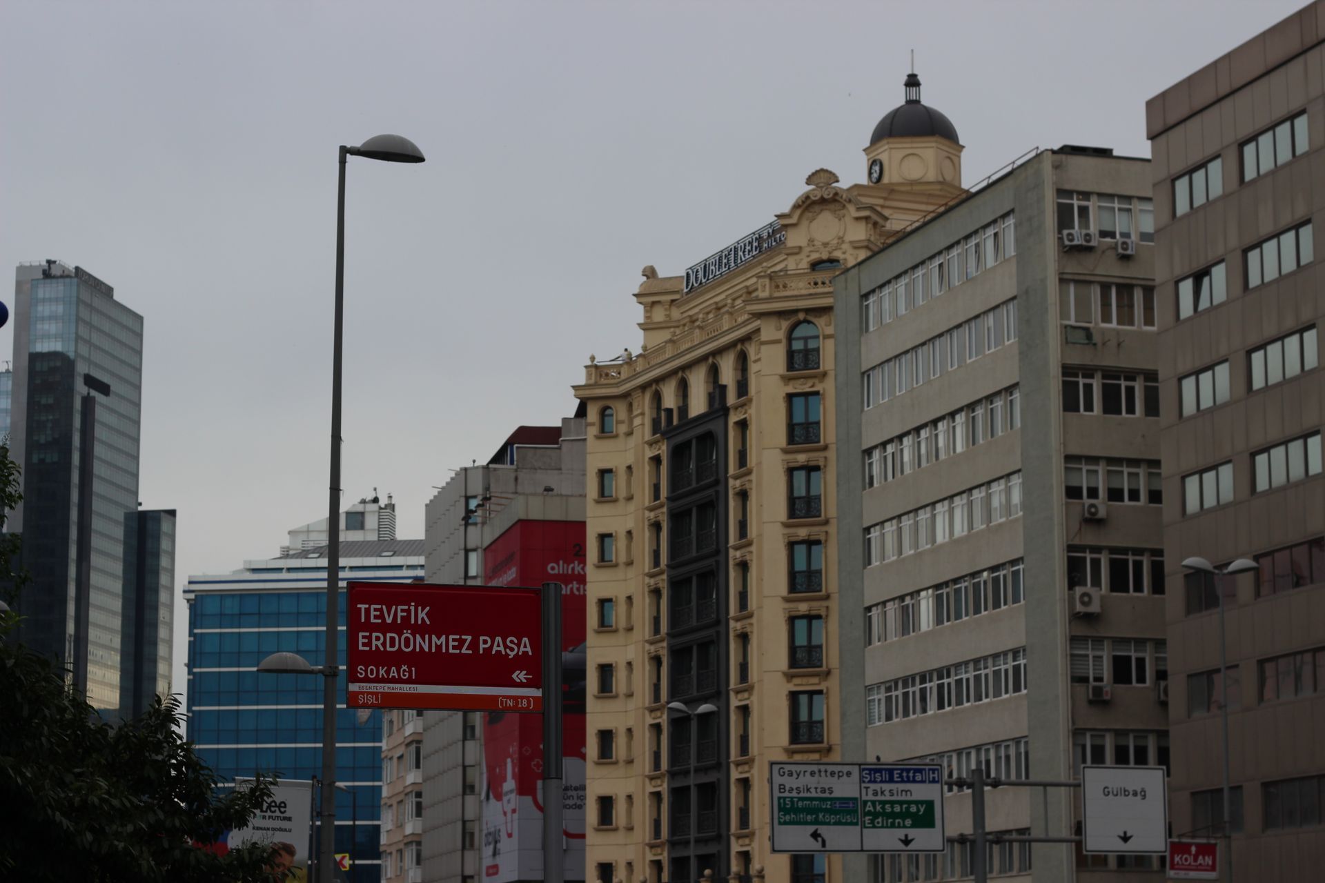 Modern multi-story luxury hotel tower with extensive glass facade and landscaped entrance grounds in the Harbiye Taksim district.
