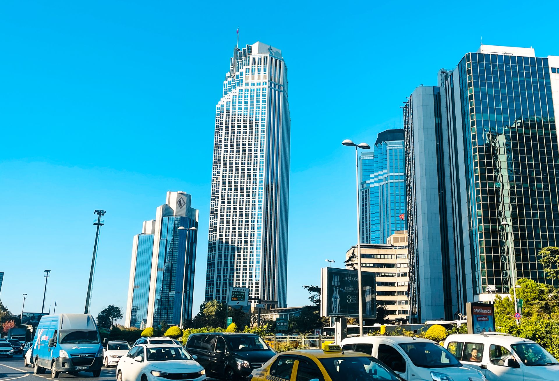 Wide urban roadway flanked by modern corporate towers and commercial headquarters.