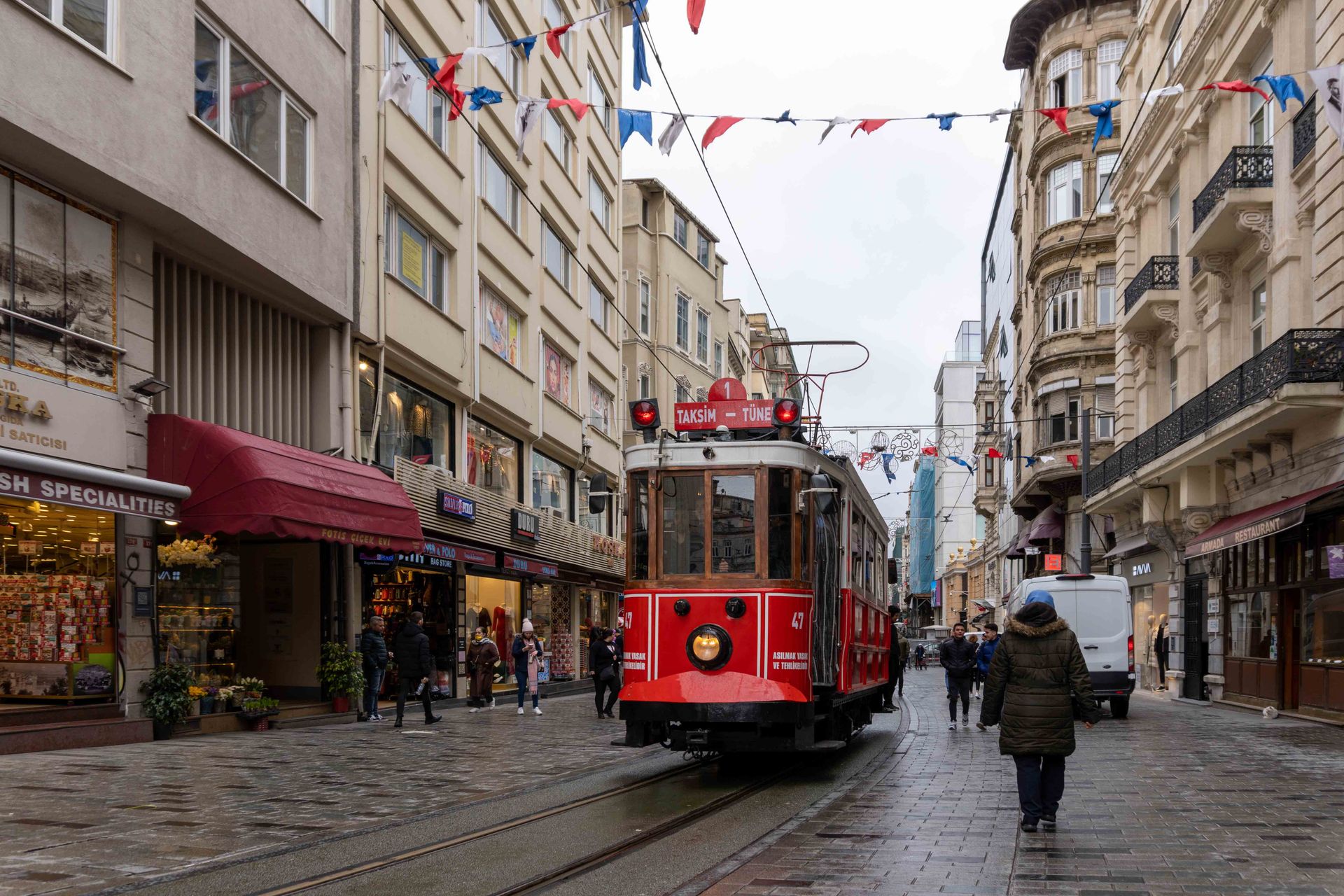 Historic red municipal tram traveling through the bustling pedestrian promenade of Istiklal Avenue in Beyoglu.