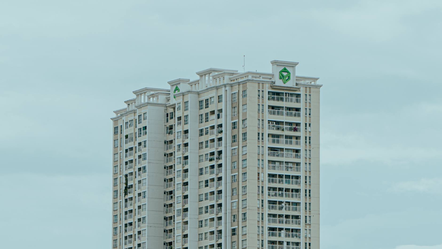 Contemporary architectural high-rise building with expansive glass windows overlooking city greenery.