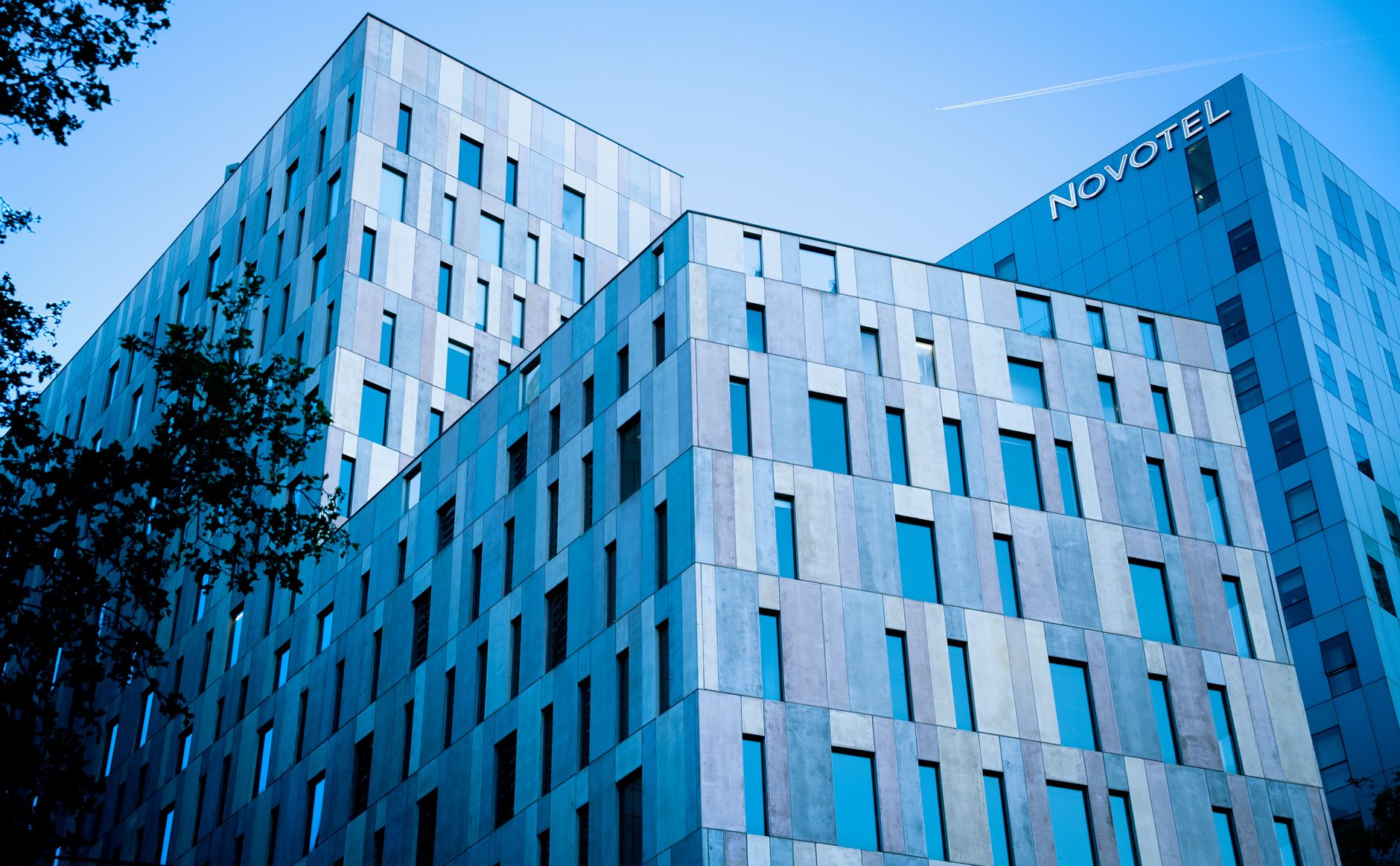 Modern urban business hotel exterior fronting a multi-lane arterial roadway with clean architectural lines.