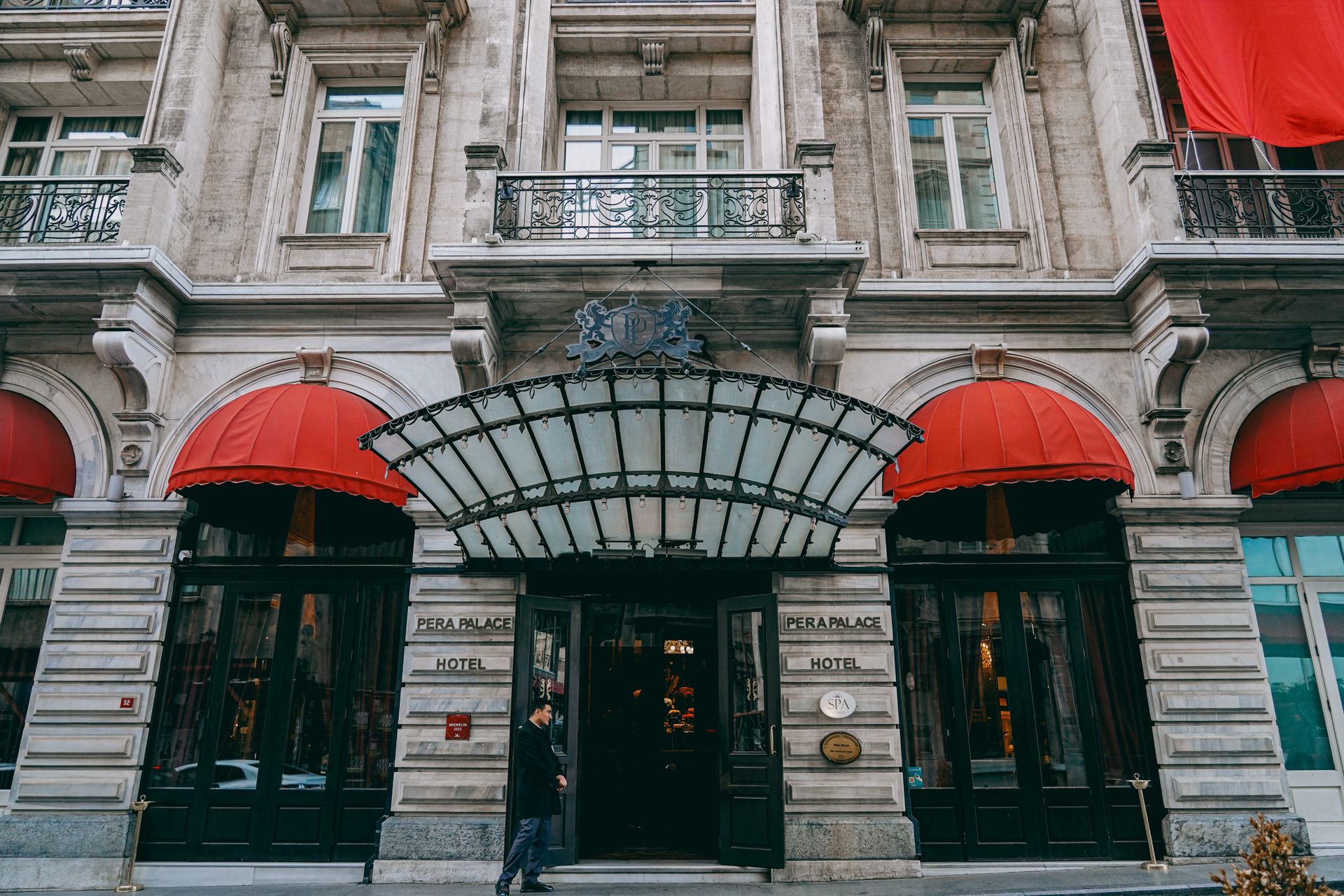Grand neoclassical entrance and facade with distinctive red awnings of the historic Pera Palace Hotel in Istanbul.