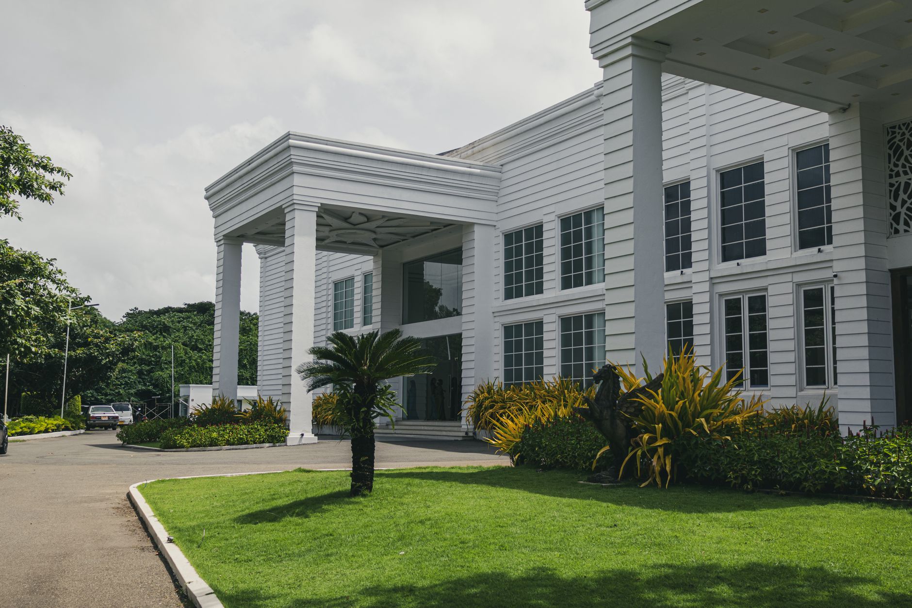 Modern city business hotel frontage featuring an elevated drop-off driveway and glass canopy.