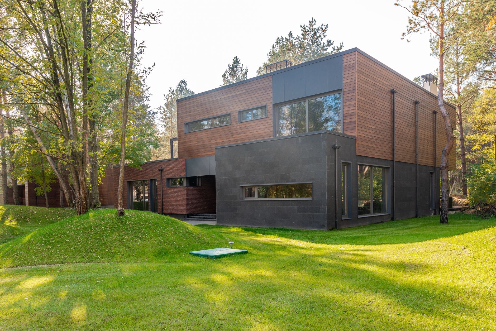 Sleek contemporary glass building facade surrounded by lush green forested hills in northern Istanbul.