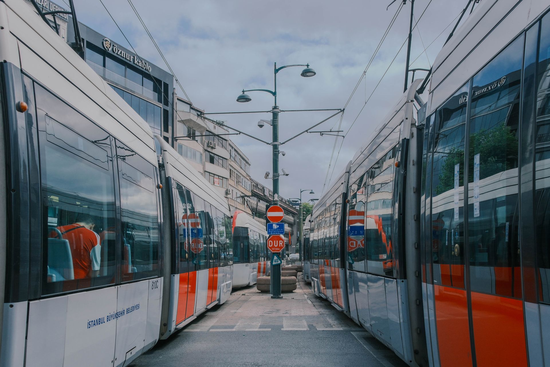 Modern public transit trams passing along a bustling historic commercial street intersection in Istanbul near Sultanahmet.