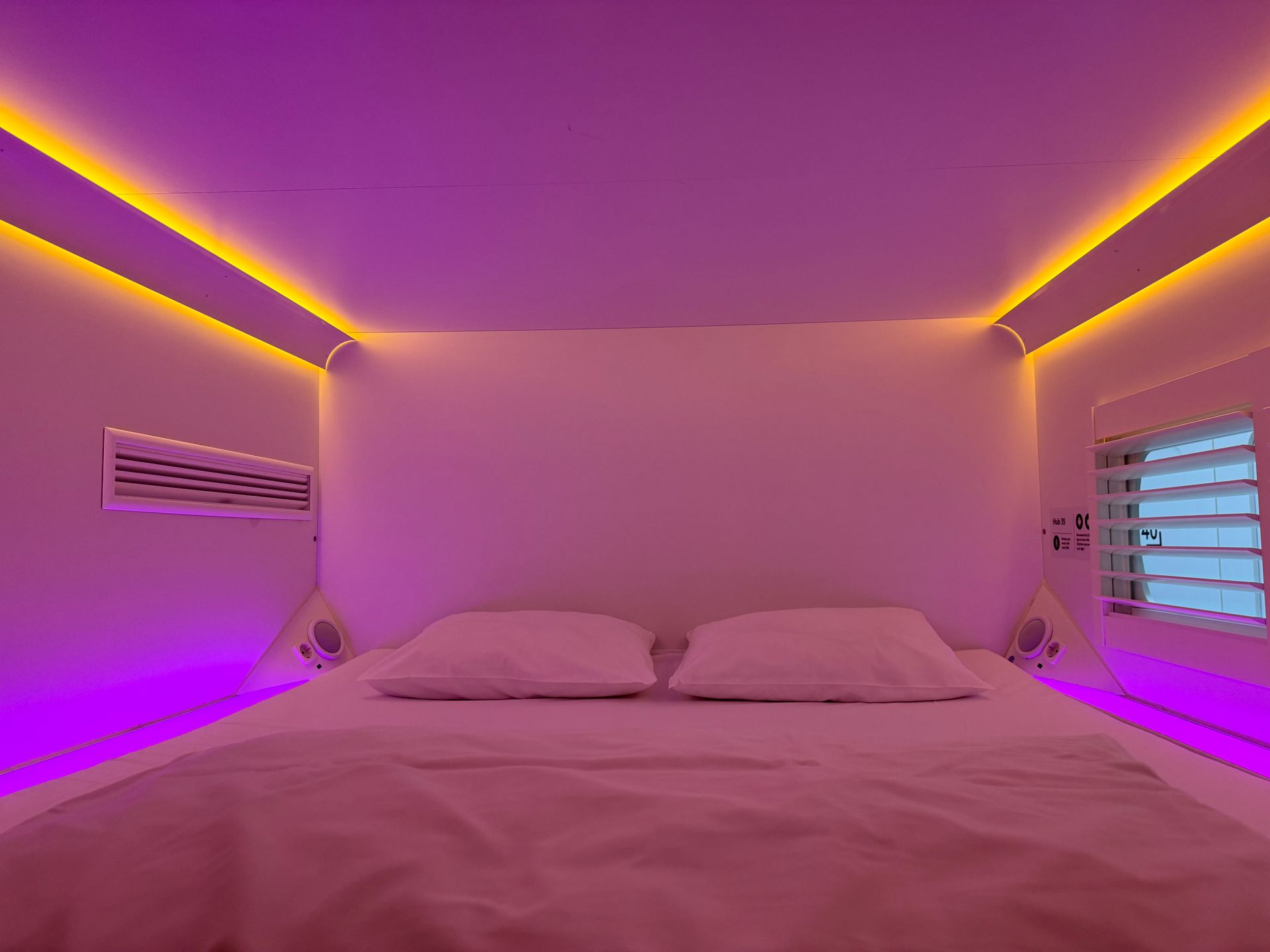 Modern compact transit hotel cabin featuring mood lighting and minimalist sleeping pod design.